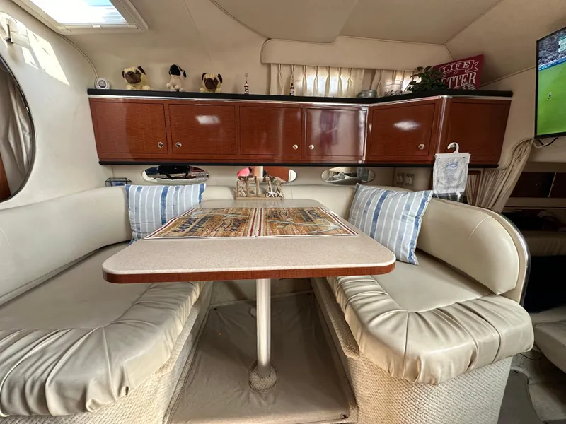 Slide: The Image of Interior of 2002 Sea Ray 310 Sundancer with cozy dining area and striped cushions. - 23