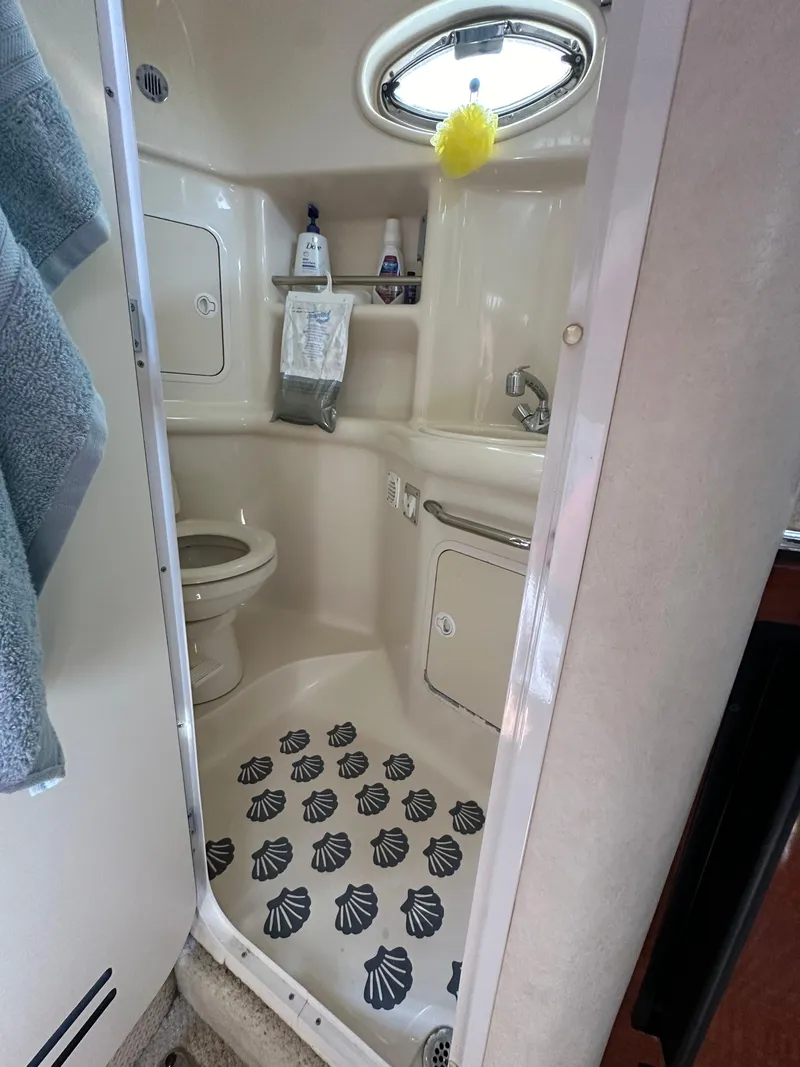 Slide: The Image of 2002 Sea Ray 310 Sundancer bathroom with shell-patterned floor and porthole window. - 25