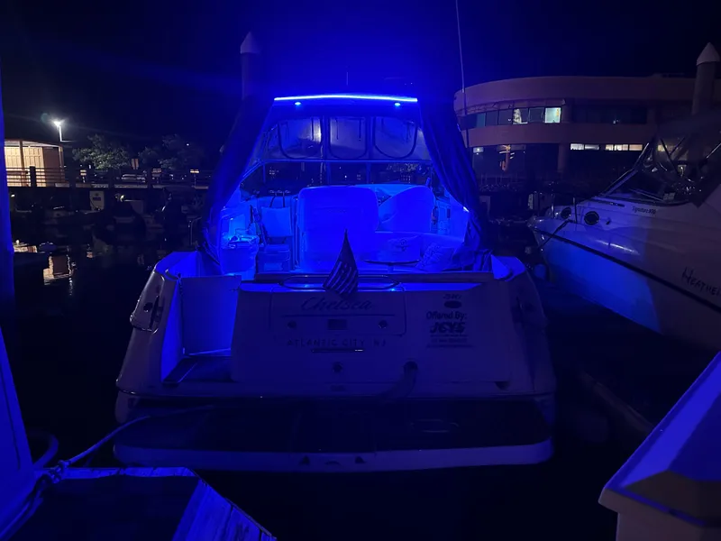 Slide: The Image of 2002 Sea Ray 310 Sundancer yacht illuminated with blue lights at night in a marina. - 40