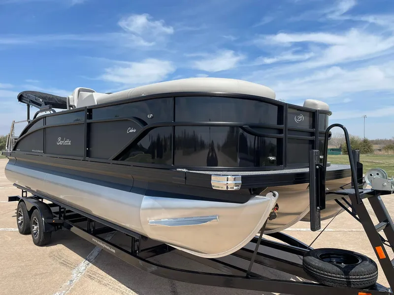 Slide: The Image of 2024 Barletta Cabrio 22UC pontoon boat on a trailer under a blue sky. - 14