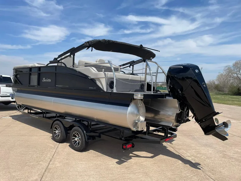 Slide: The Image of 2024 Barletta Cabrio 22UC pontoon boat with black exterior and outboard motor on trailer. - 6