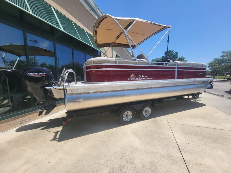 The Image of 2024 Sun Tracker Party Barge 24 DLX pontoon boat on trailer, parked outdoors. - 0
