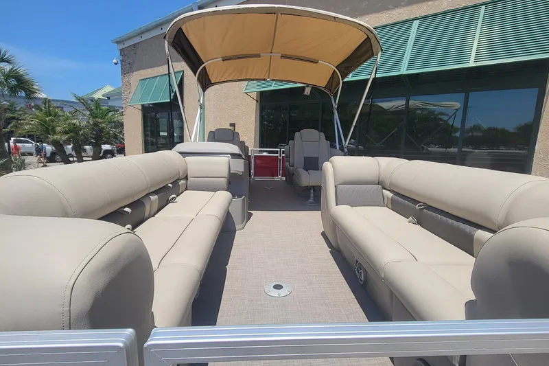 Slide: The Image of 2024 Sun Tracker Party Barge 24 DLX pontoon boat on trailer, parked outdoors. - 2