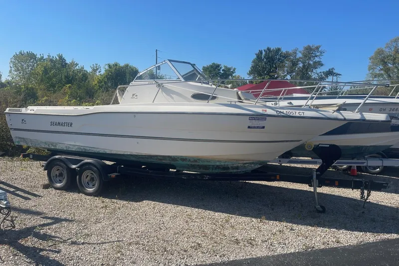 The Image of 2000 Seamaster 2388 WA boat on trailer, parked outdoors on gravel. - 0