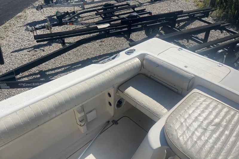 Slide: The Image of 2000 Seamaster 2388 WA boat interior with white seating and nearby trailers. - 8