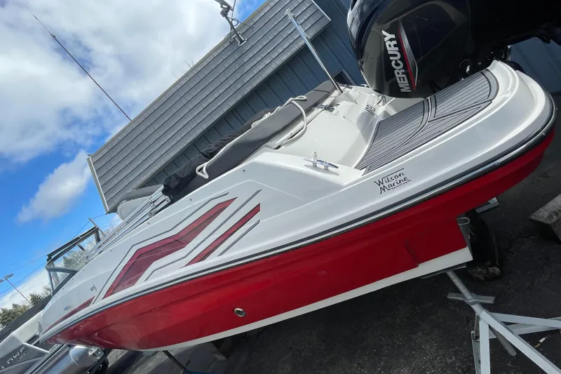 Slide: The Image of 2021 Bayliner VR5 boat with red and white exterior, docked near a building. - 4