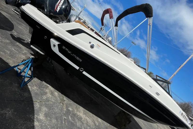 Slide: The Image of 2021 Bayliner VR5 boat on a stand, black and white exterior, outboard motor. - 8
