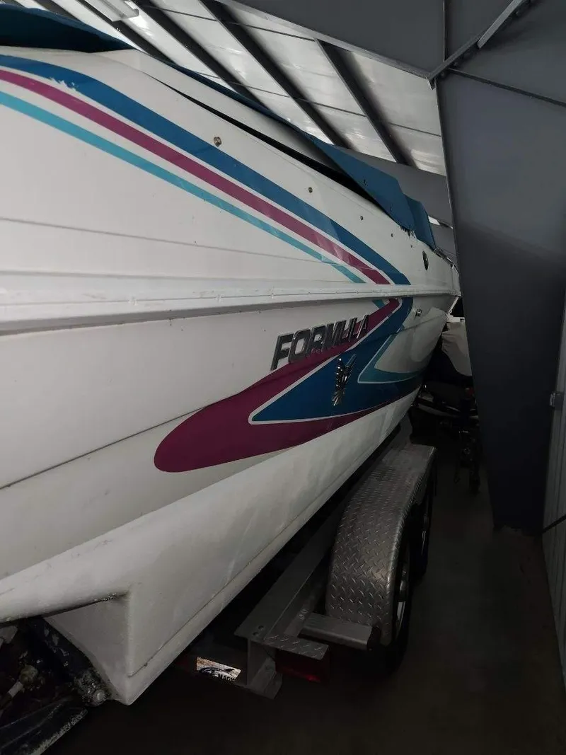 Slide: The Image of 1993 Formula 303 SR1 boat with colorful stripes on trailer in storage. - 11
