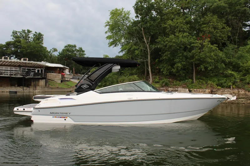 Slide: The Image of 2023 Monterey 298SS boat on a calm lake near a wooded shoreline. - 19