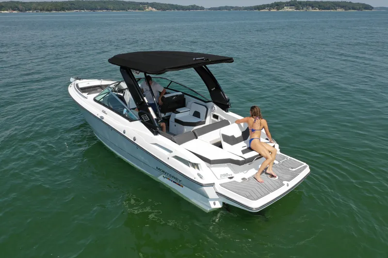 Slide: The Image of 2023 Monterey 298SS boat on a lake with a woman sunbathing on the deck. - 2