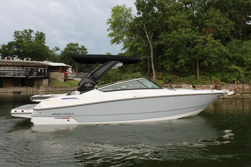 Slide: The Image of 2023 Monterey 298SS boat on a calm lake with lush green trees in the background. - 20