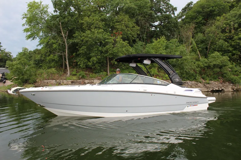 Slide: The Image of 2023 Monterey 298SS boat cruising on a lake with lush green trees in the background. - 25