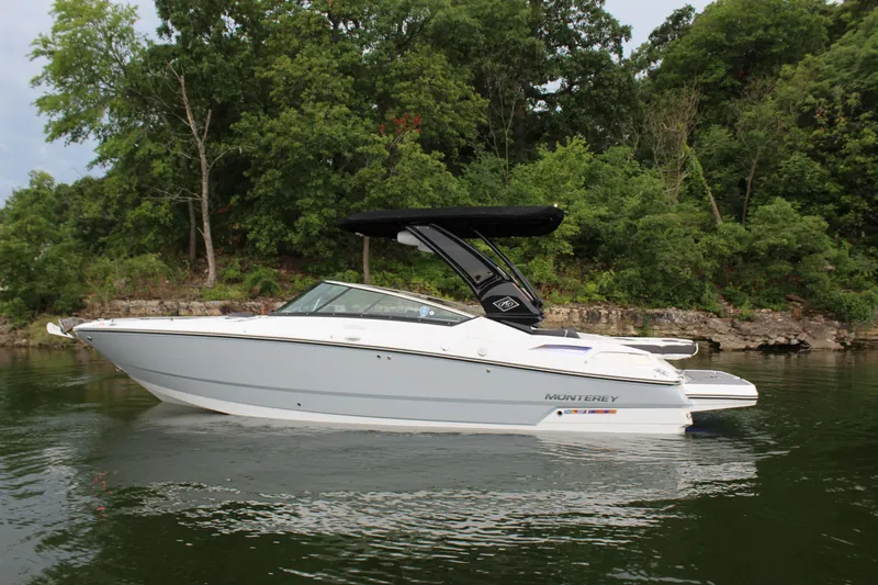Slide: The Image of 2023 Monterey 298SS boat on a calm lake with a forested shoreline. - 30