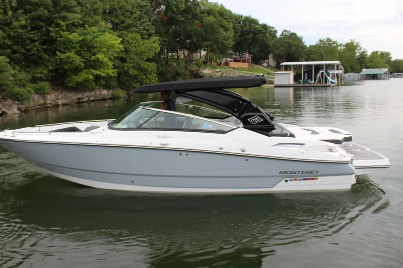 Slide: The Image of 2023 Monterey 298SS boat cruising on a lake with lush green trees in the background. - 31