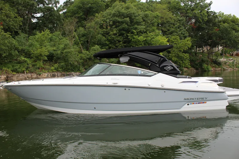 Slide: The Image of 2023 Monterey 298SS boat on a lake with lush green trees in the background. - 32