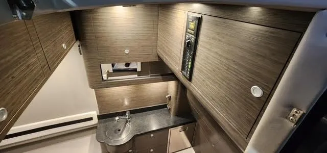 Slide: The Image of 2024 Mystic Powerboats 42 CC interior cabin with modern wood finish and compact kitchenette. - 5