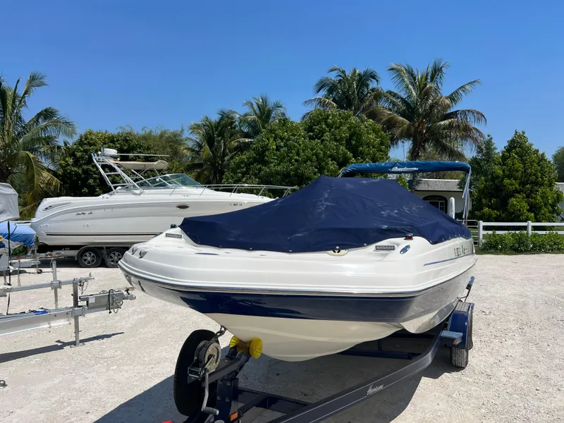 Slide: The Image of 2007 Hurricane 231 boat on trailer with cover, parked near palm trees. - 6