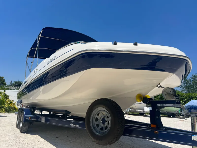 Slide: The Image of 2007 Hurricane 231 boat on trailer with blue canopy under clear sky. - 8