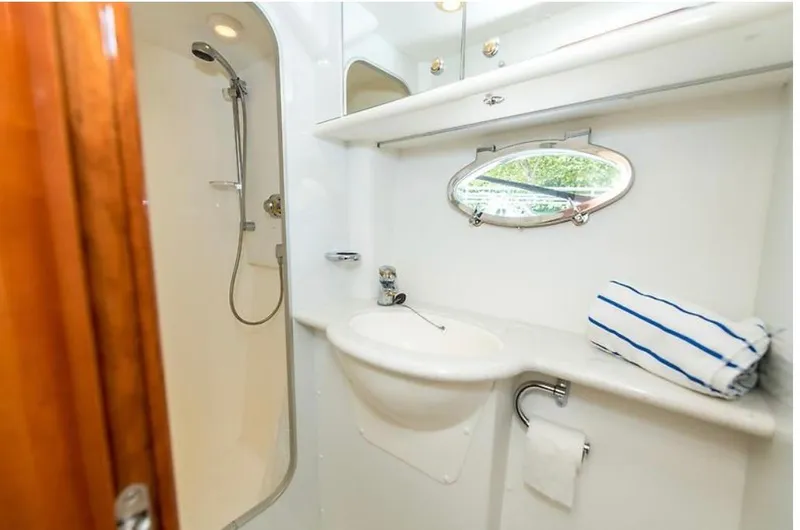 Slide: The Image of Bathroom interior of 1997 Sunseeker Manhattan yacht with shower, sink, and porthole window. - 24