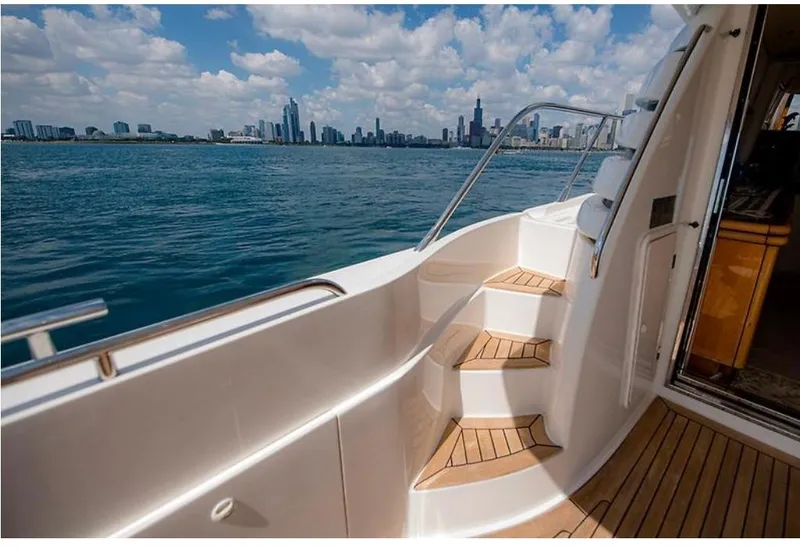 Slide: The Image of 1997 Sunseeker MANHATTAN yacht with city skyline view, featuring elegant wooden steps and deck. - 34