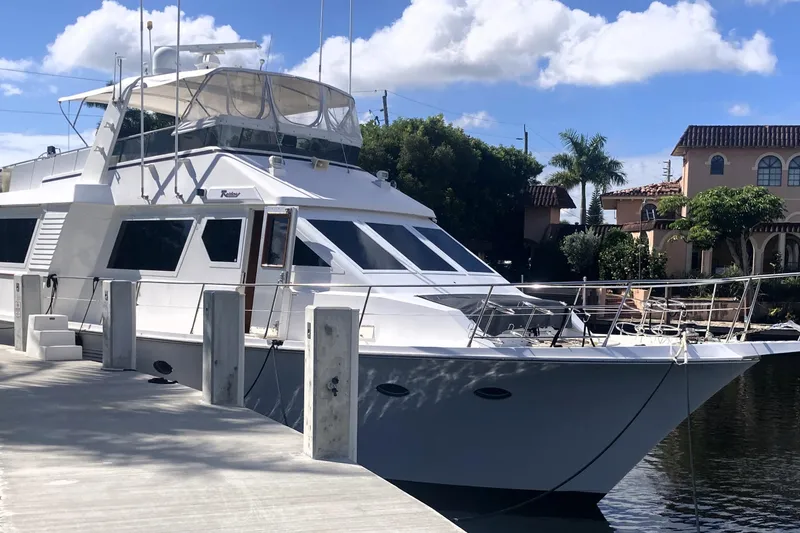Slide: The Image of 1988 Viking 70 Cockpit Motor Yacht docked by waterfront homes under a blue sky. - 13