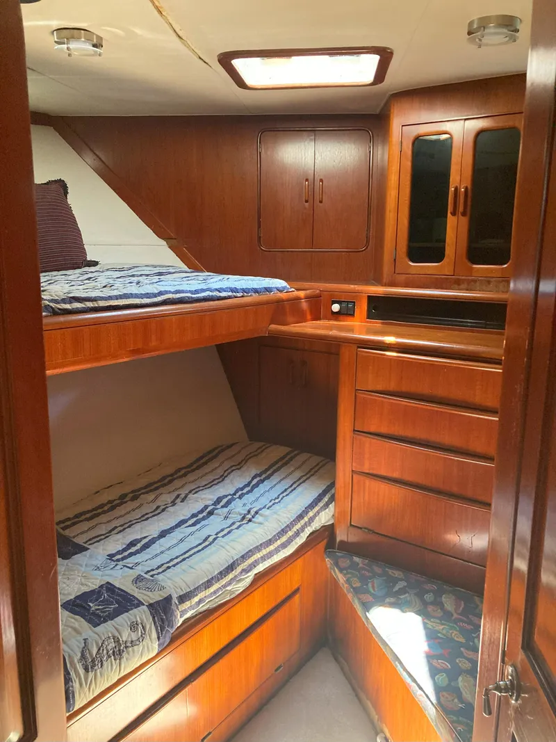 Slide: The Image of 1988 Viking 70 Cockpit Motor Yacht cabin with wooden bunk beds and storage. - 35