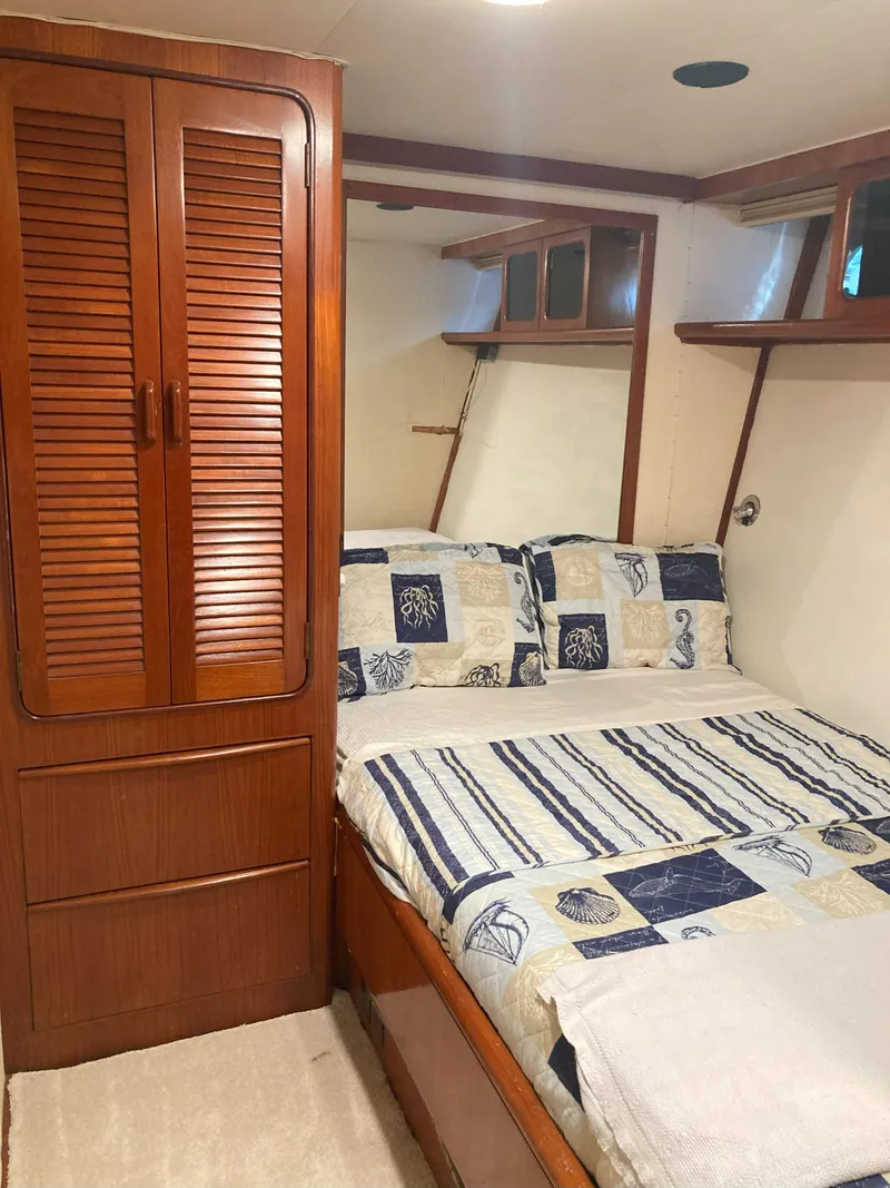 Slide: The Image of Cozy bedroom in a 1988 Viking 70 Cockpit Motor Yacht with wooden cabinetry. - 43
