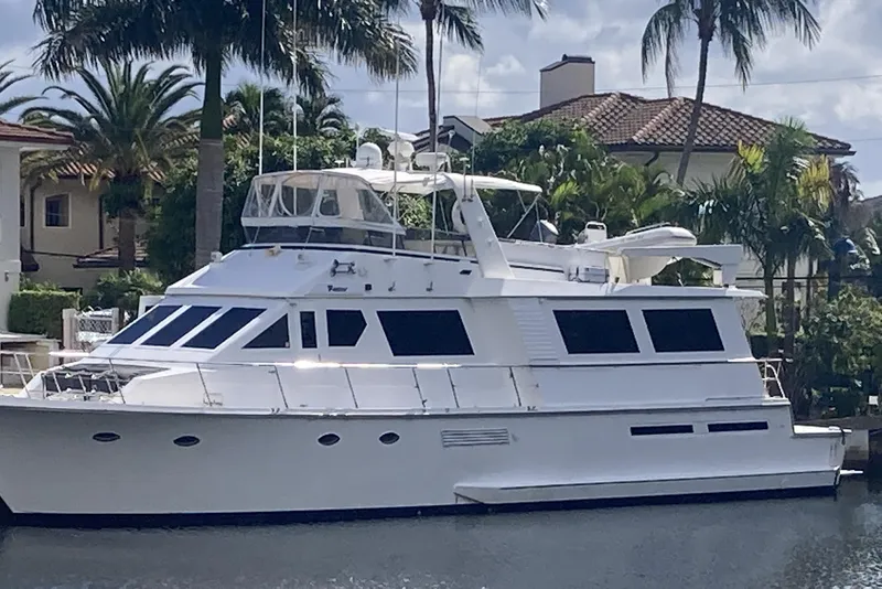 Slide: The Image of 1988 Viking 70 Cockpit Motor Yacht docked near palm trees and luxury homes. - 5