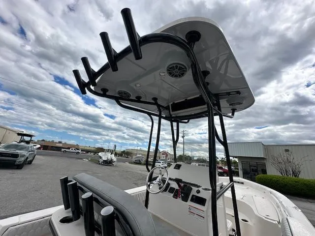 Slide: The Image of 2024 Carolina Skiff 23 LX boat with T-top and rod holders, docked under cloudy sky. - 9