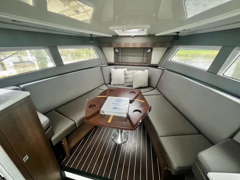 Slide: The Image of 2018 Monterey 360 Sport Coupe interior with grey seating and wooden table. - 12