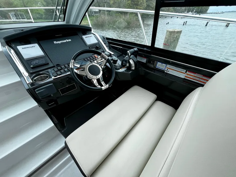 Slide: The Image of 2018 Monterey 360 Sport Coupe helm with Raymarine electronics, leather seating, and waterfront view. - 7