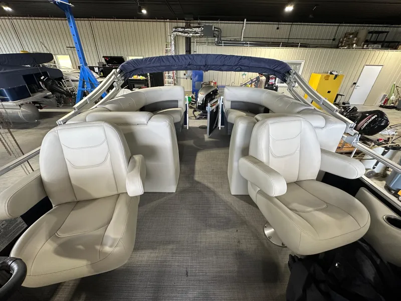 Slide: The Image of 2024 Starcraft LX22RDH pontoon boat interior with beige seating in a showroom. - 2