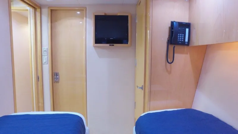 Slide: The Image of Interior of 2006 Hatteras Enclosed Bridge yacht cabin with twin beds, TV, and phone. - 15