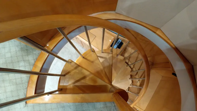Slide: The Image of Spiral staircase inside 2006 Hatteras Enclosed Bridge yacht, featuring wooden steps and metal railings. - 20