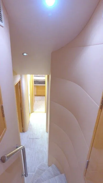 Slide: The Image of Interior view of 2006 Hatteras Enclosed Bridge yacht, featuring a curved staircase and hallway. - 8