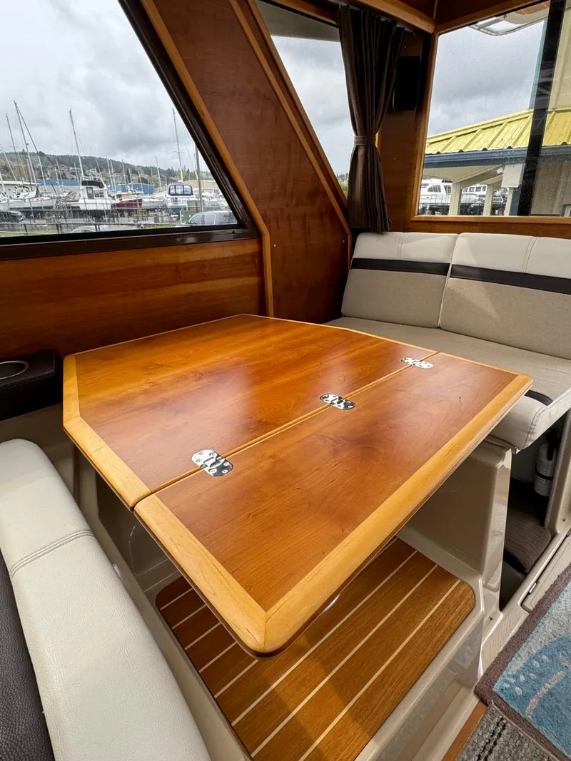 Slide: The Image of 2017 Cutwater C28 interior with wooden table and seating, dock view in background. - 15