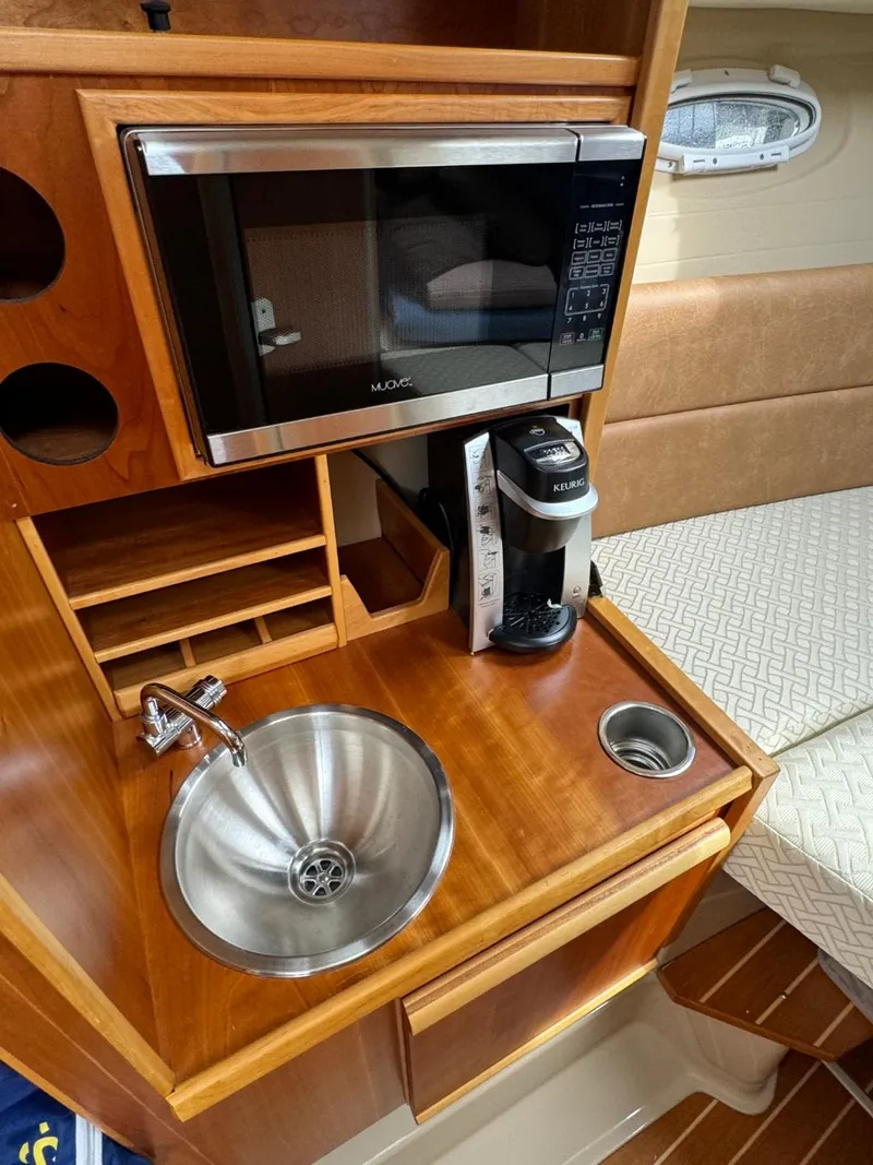Slide: The Image of 2017 Cutwater C28 galley with microwave, sink, and coffee maker on wooden countertop. - 31