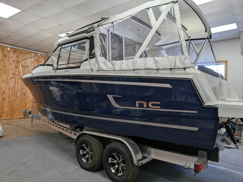 The Image of 2024 Jeanneau NC795 S2 boat on trailer in showroom setting. - 1