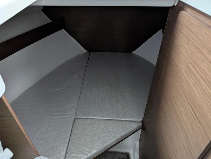 Slide: The Image of 2024 Jeanneau NC795 S2 cabin interior with gray cushions and wood paneling. - 4