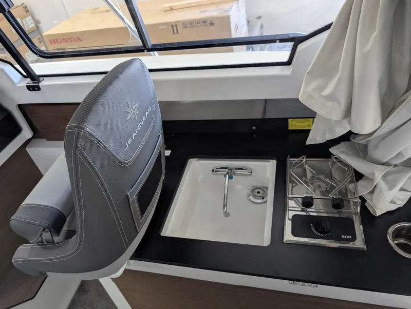 Slide: The Image of 2024 Jeanneau NC795 S2 interior with sink and stove in compact kitchen area. - 8