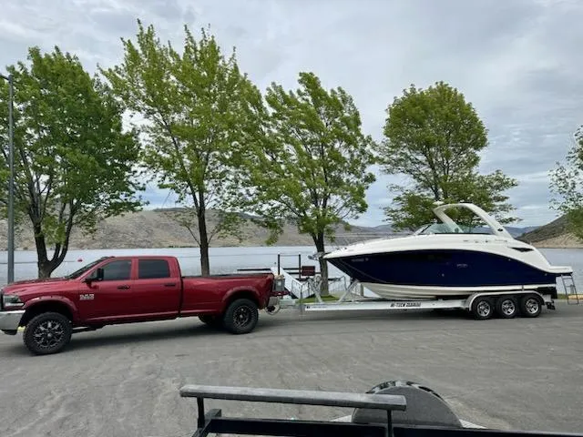 Slide: The Image of Red truck towing 2015 Sea Ray 260 Sundancer boat on trailer by a lake. - 0