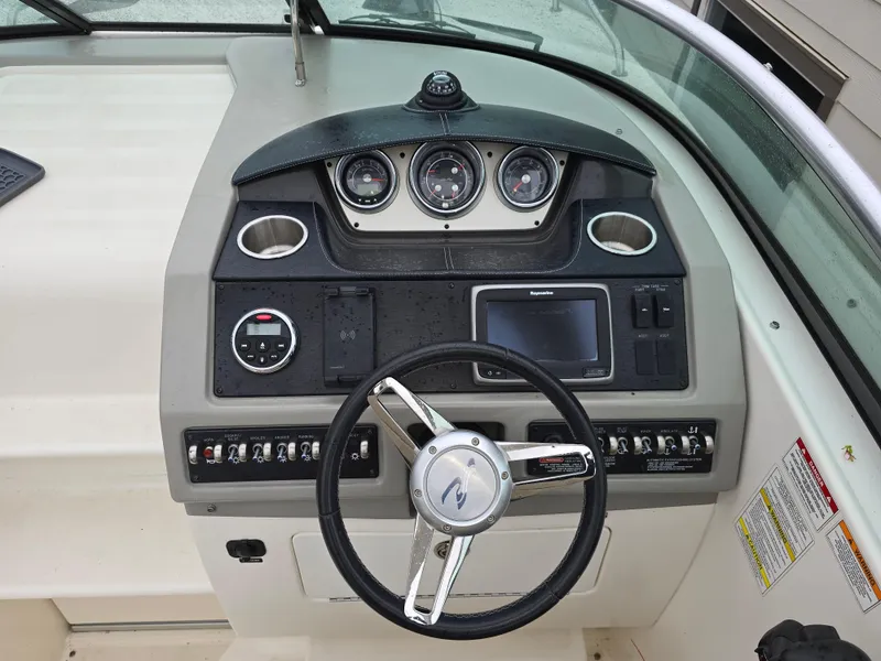 Slide: The Image of 2015 Sea Ray 260 Sundancer boat dashboard with steering wheel and control panel. - 1