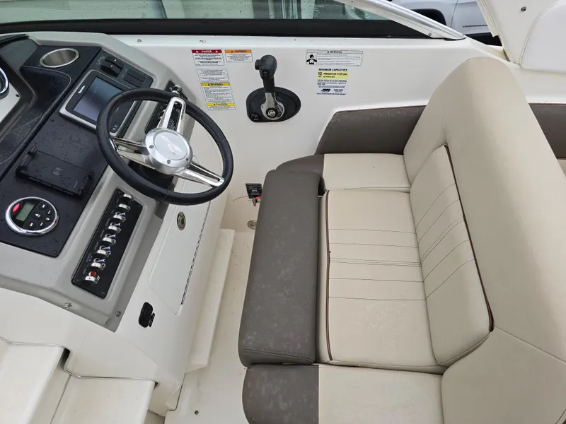Slide: The Image of 2015 Sea Ray 260 Sundancer helm with steering wheel and beige seating. - 2