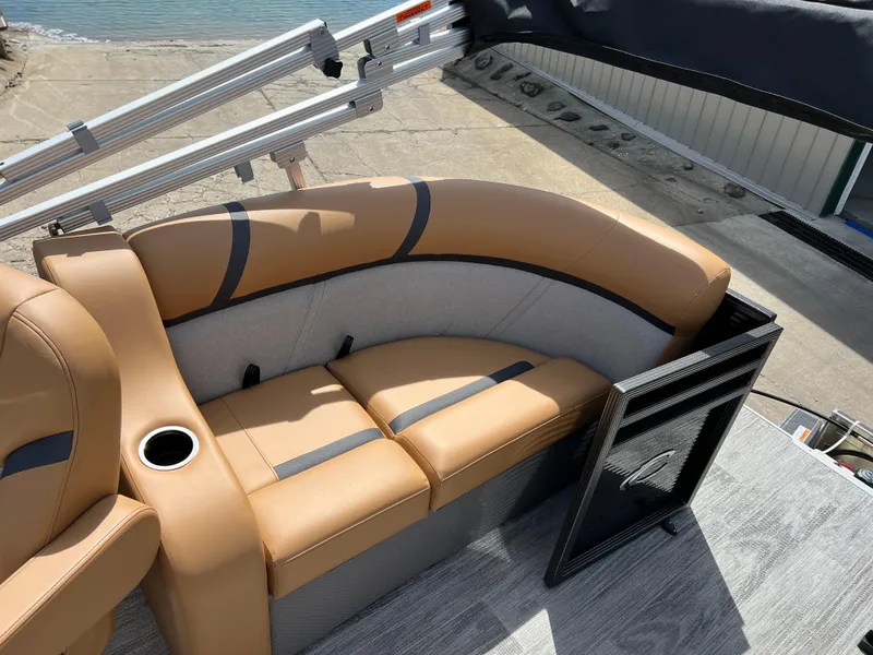 Slide: The Image of 2024 Crest Classic LX 220 boat with tan and gray seating, cup holder, and dockside view. - 10