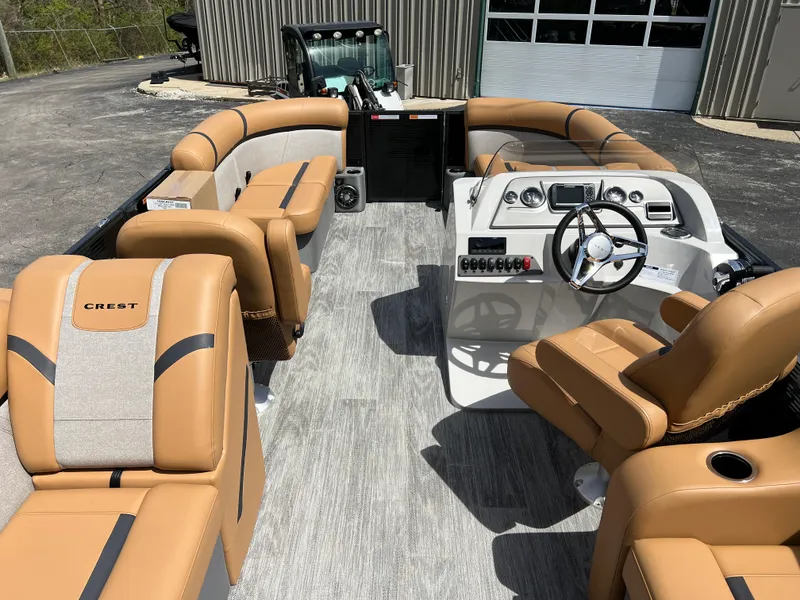Slide: The Image of 2024 Crest Classic LX 220 pontoon boat interior with tan seating and modern dashboard. - 13