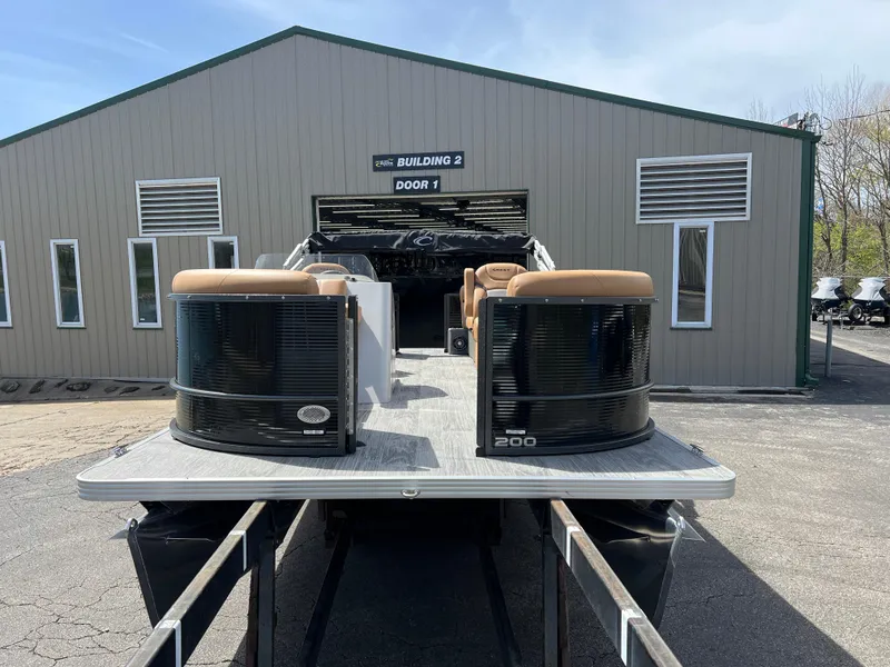 Slide: The Image of 2024 Crest Classic LX 220 pontoon boat on trailer outside a storage building. - 3