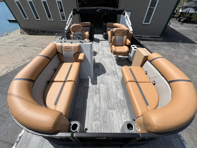 Slide: The Image of 2024 Crest Classic LX 220 pontoon boat with tan leather seating and spacious deck. - 6