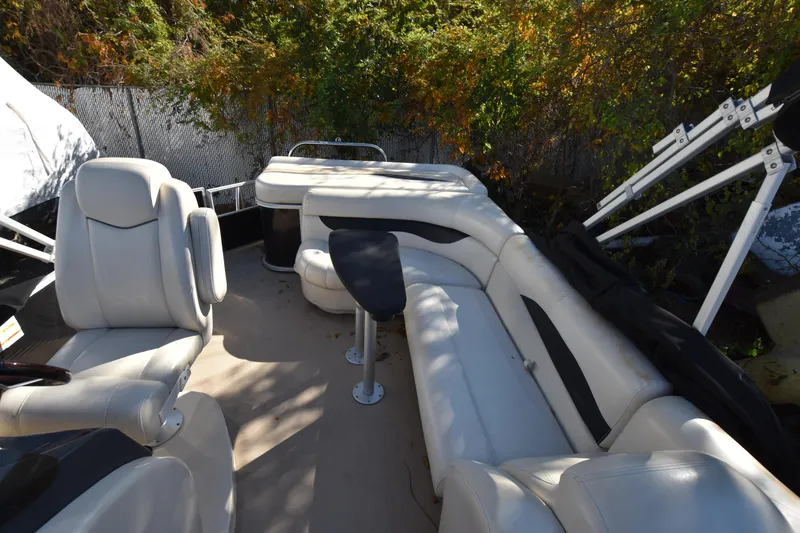 Slide: The Image of 2014 AquaPatio 240 boat interior with white seating and table, surrounded by greenery. - 29
