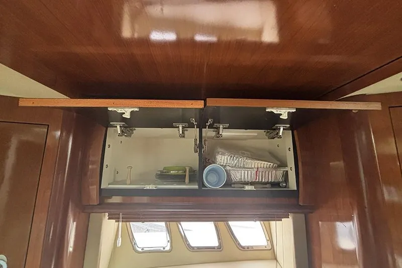 Slide: The Image of Open wooden cabinet in 2006 Sea Ray 44 Sundancer yacht interior, showing stored kitchen items. - 27