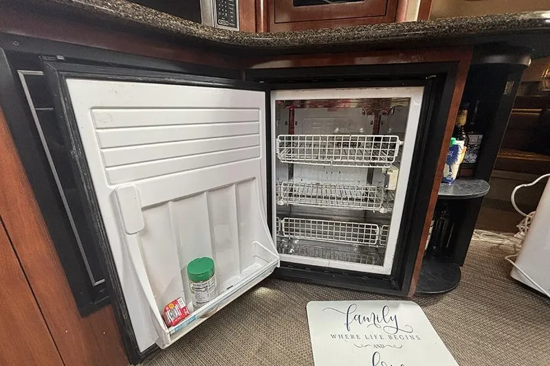 Slide: The Image of Open refrigerator inside 2006 Sea Ray 44 Sundancer yacht, with minimal contents and wooden cabinetry. - 30